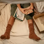 Child sitting under blanket sorting greeting cards, cozy setting indoors.
