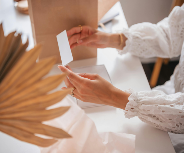 A person with lace long sleeves opening a white box at a table.